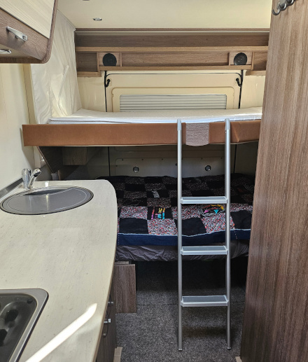 Bürstner Brevio -matkailuauton takaosa: pöytäryhmä on muutettu vuoteeksi ja lisävuode on vedetty alas niin että muodostuu kerrossänky