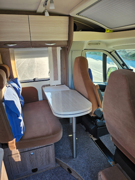 Bürstner Brevio -matkailuauton etuosa: ohjaamon penkit, joiden takana on pöytä ja lisäpenkit