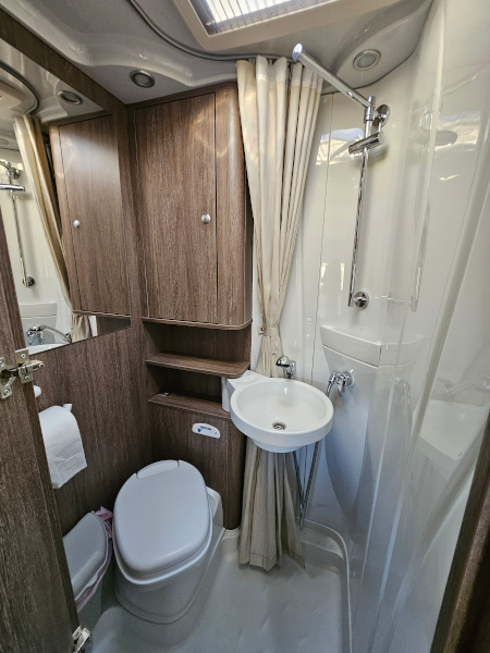 Bürstner Brevio -matkailuauton wc ja pesutila, jossa on wc. peili, kaappi, suihkuverho ja suihku.